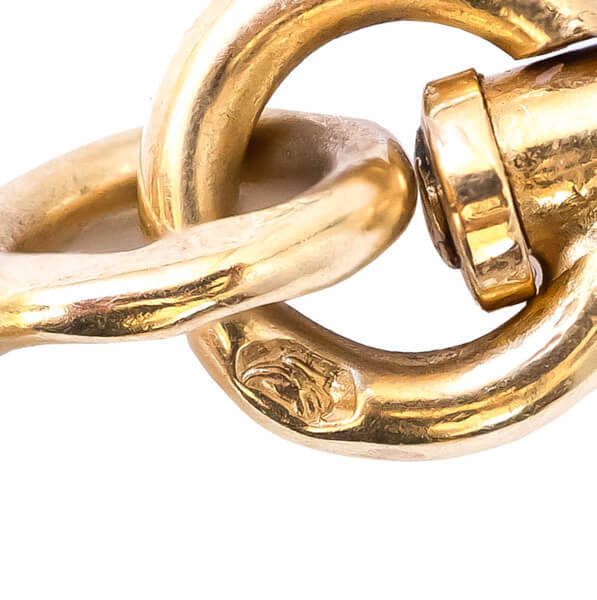 A close-up view of an eagle stamped hallmark on a gold jump ring